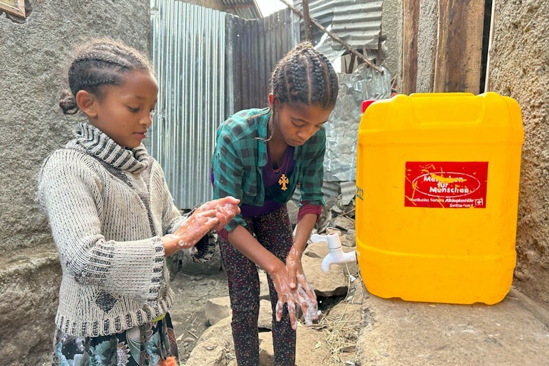 Mädchen waschen Hände an einem Kanister der Stiftung Menschen für Menschen
