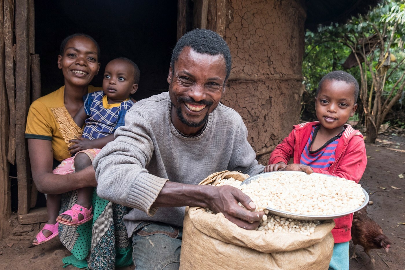 Bauernfamilie: Vater zeigt stolz einen Sack mit Getreidekörnern