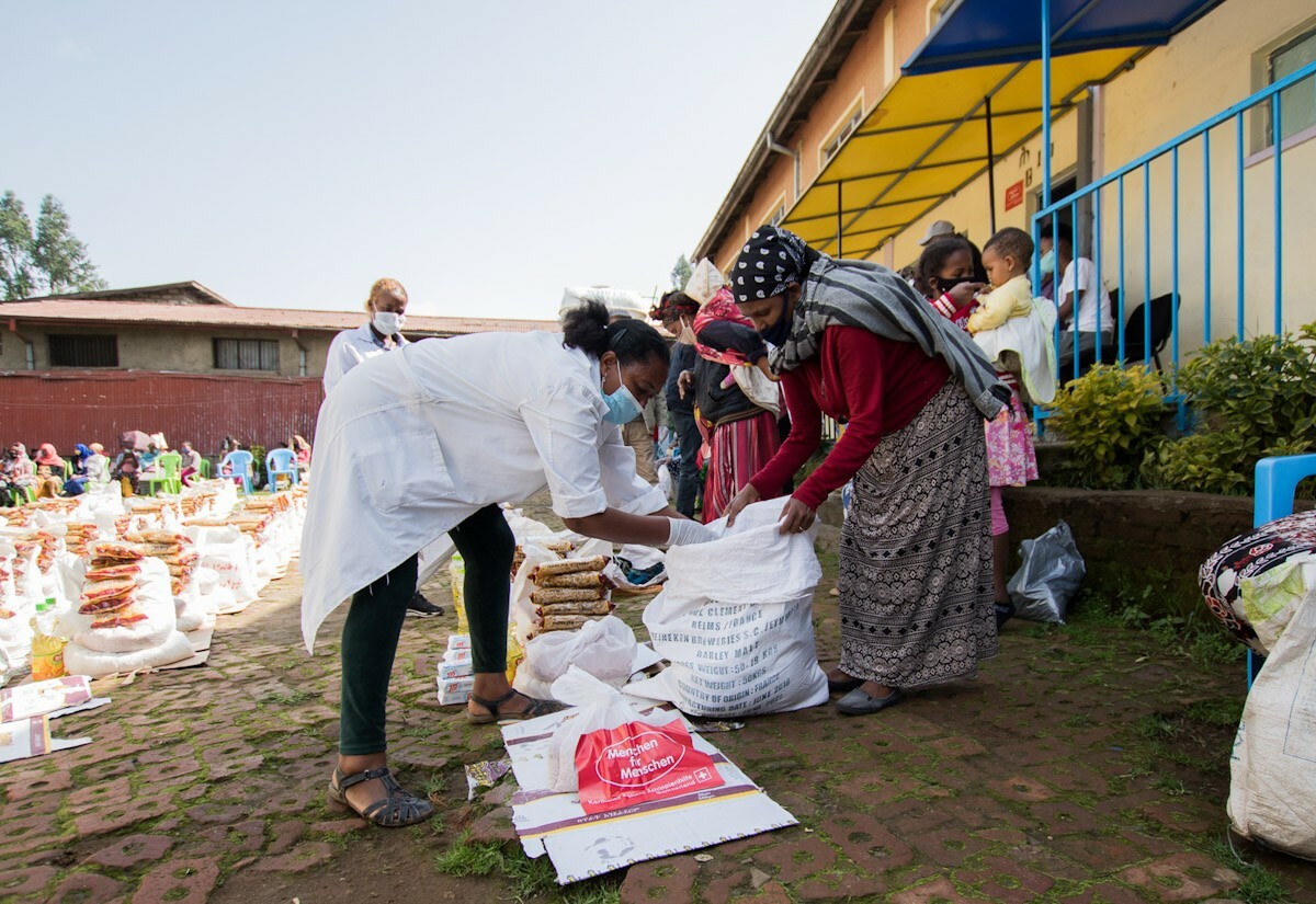 Eine arme Frau mit Gesichtsmaske erhält ein Nothilfe-Paket