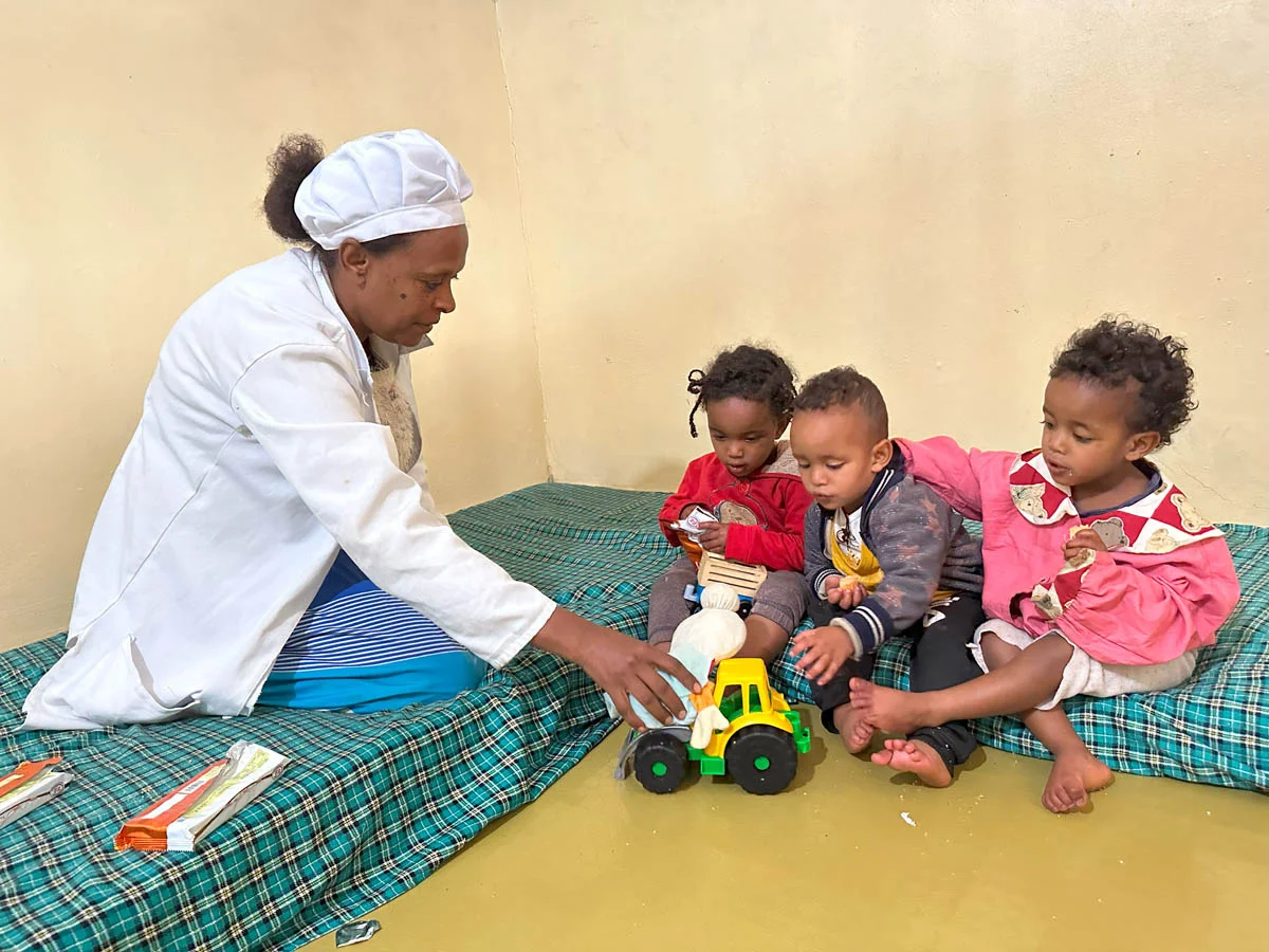Kinderbetreuerin spielt mit den Drillingen in der Krippe von Menschen für Menschen in Addis Abeba Kinderbetreuerin spielt mit den Drillingen in der Krippe