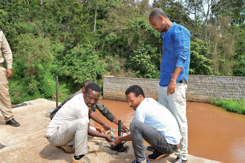 Mitarbeiter am Bau öffnen symbolisch den Durchlass vom Wehr zum Bewässerungskanal