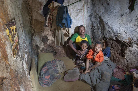 Vater mit zwei Kindern in einer winzigen Wohnung im Slum