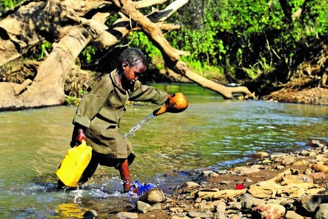 Junge trägt Wasserkanister aus dem Fluss