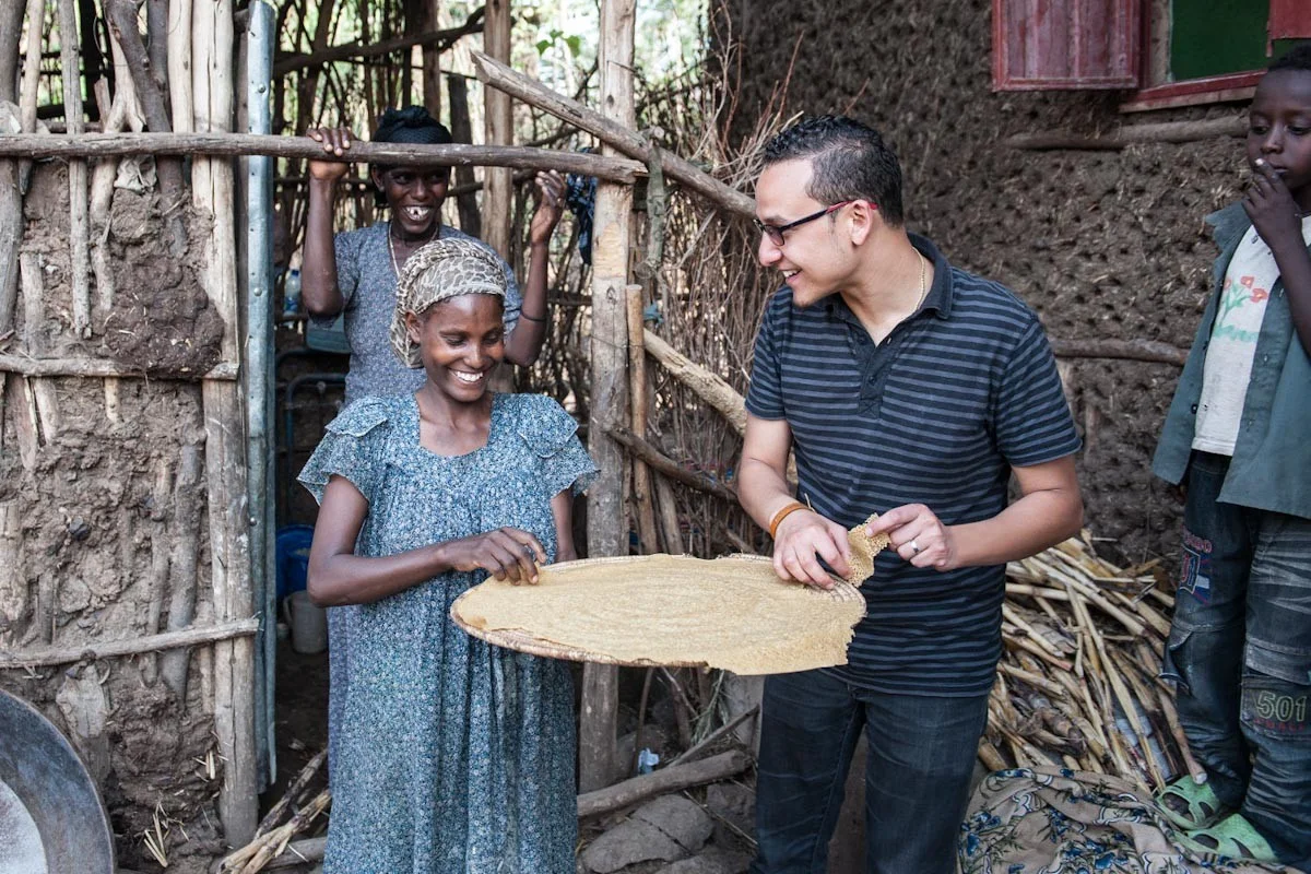 A woman offers a man injera