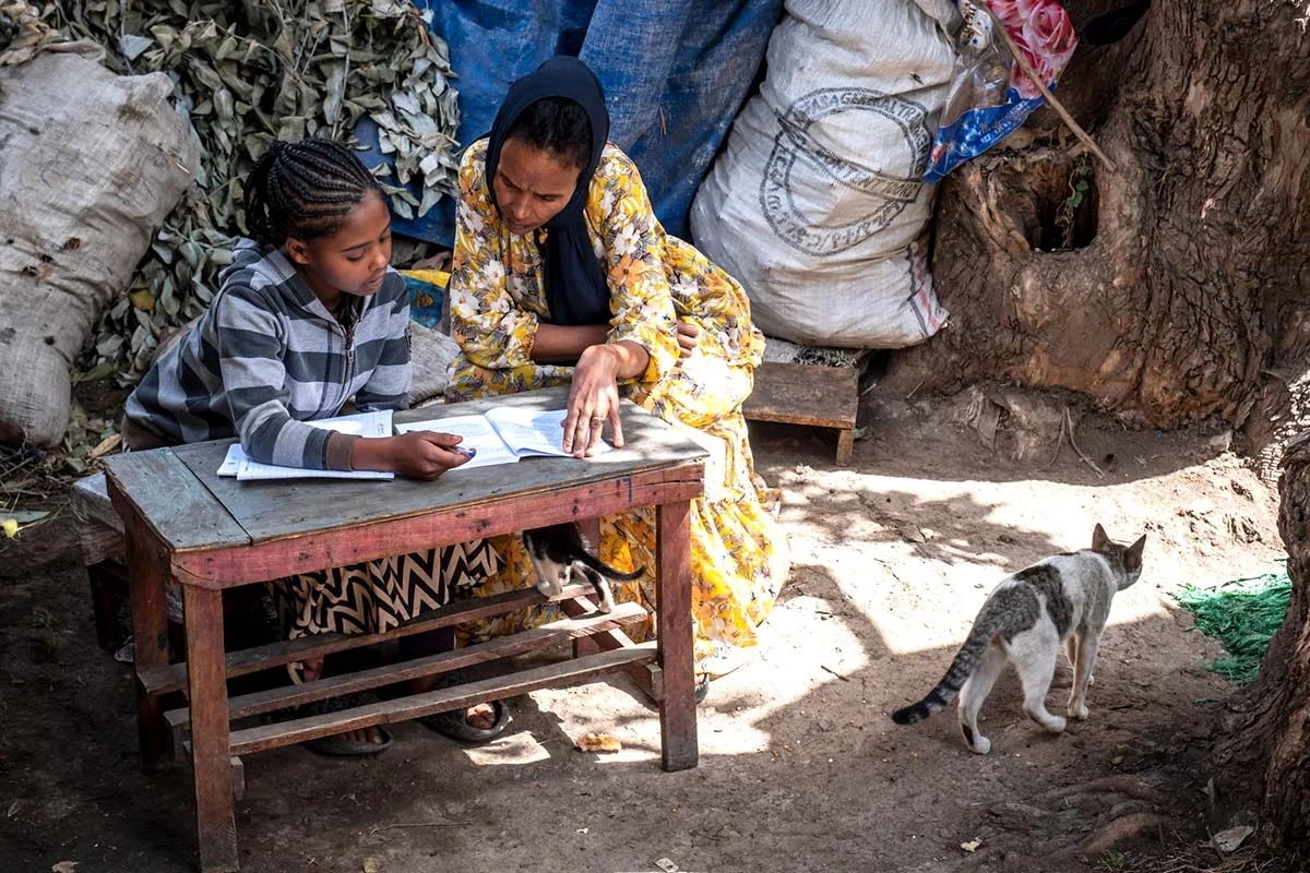 Social worker supports children in Debre Berhan | Menschen für Menschen Foundation Social worker sits next to Tebka and helps her with her diary