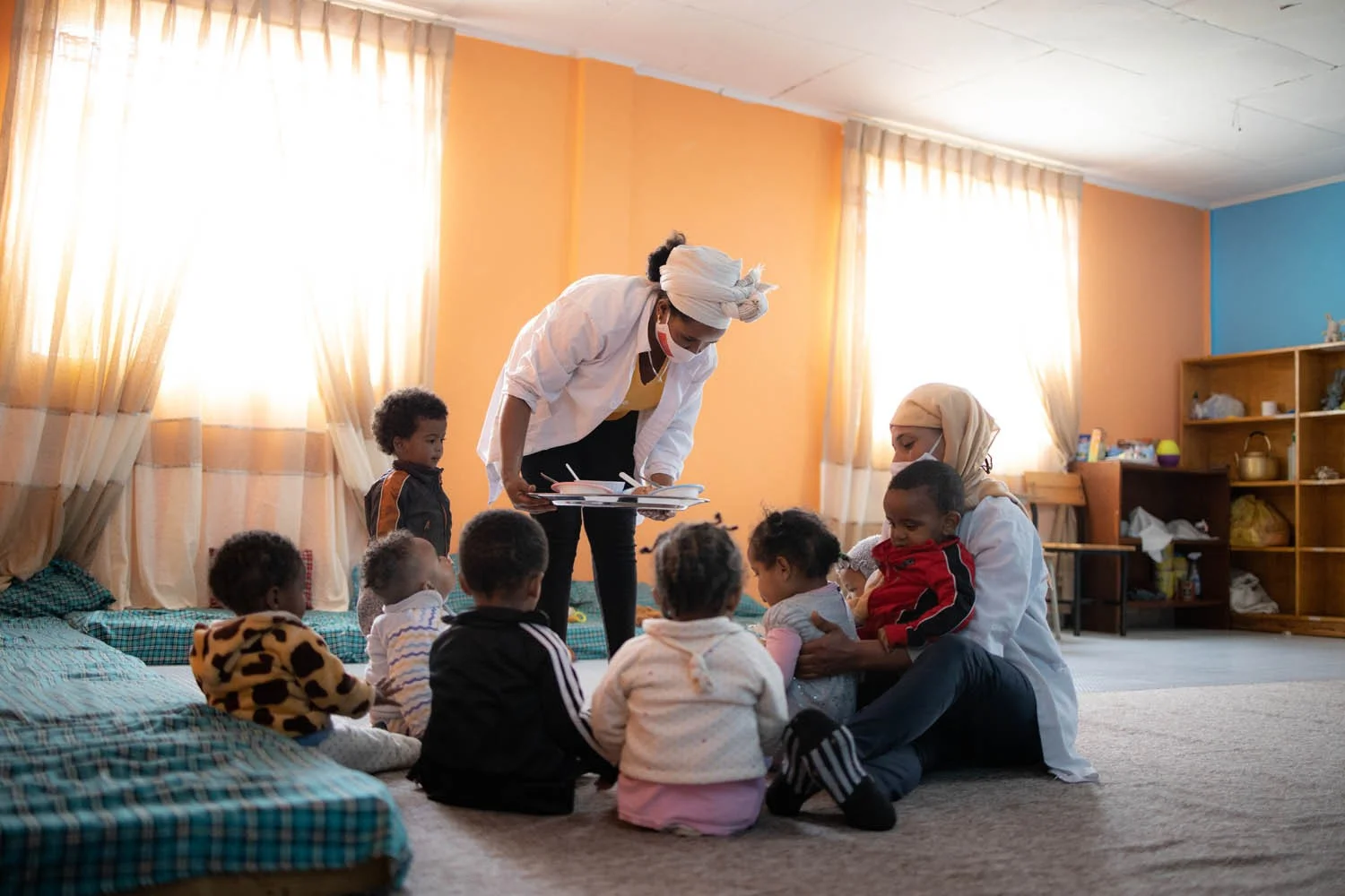 Kinder mit Betreuerinnen in der Krippe