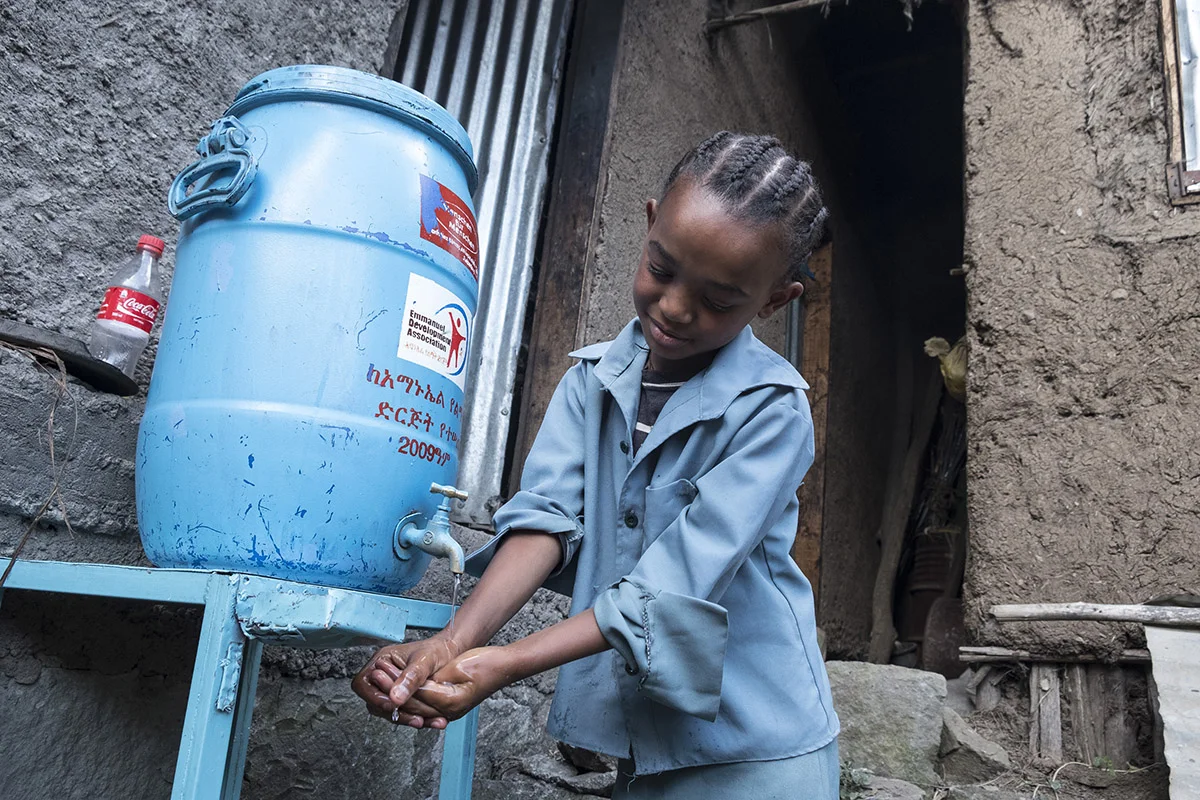 Mädchen wäscht ihre Hände dank einem Wasserkanister von der Stiftung