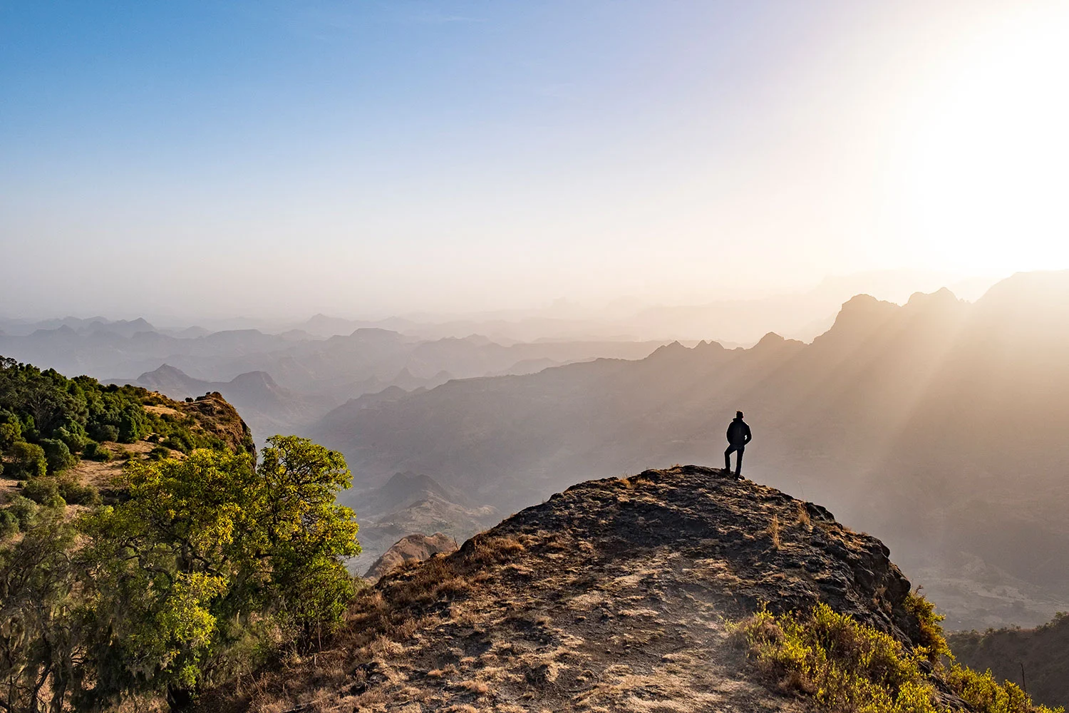 Mann auf Berg mit Sonnenstrahlen