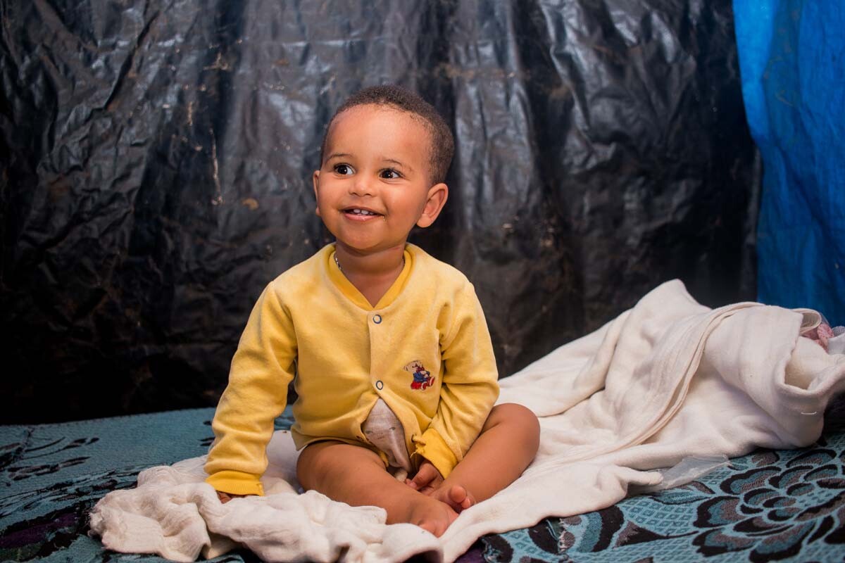 Kleinkind sitzt am Boden - Stiftung Menschen für Menschen