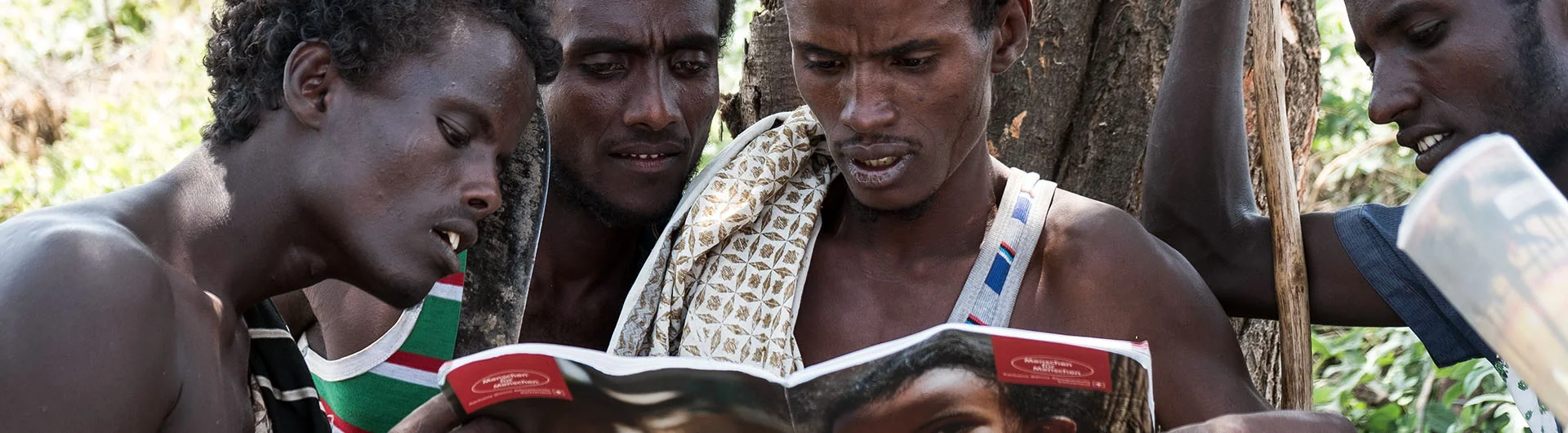 Afar-Nomaden betrachten einen Jahresbericht der Stiftung Menschen für Menschen