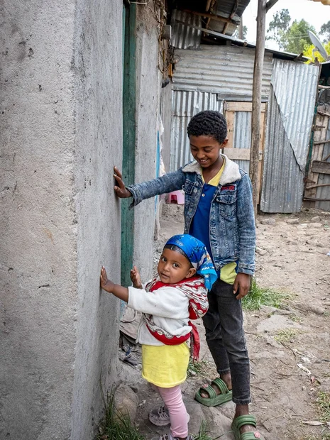 Biruk und seine kleine Schwester halten Hand an die Mauer