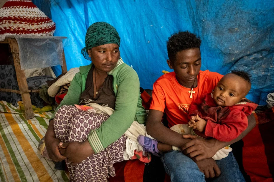 Junge hält den kleinen Bruder im Arm und Mutter sitzt neben dran