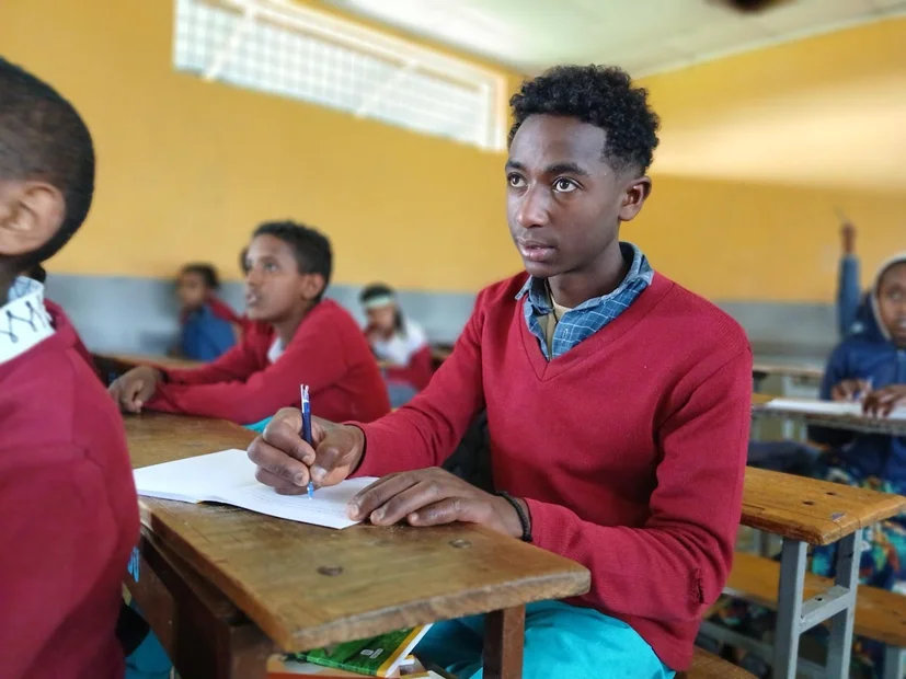 Ayele macht Notizen im Schulunterricht