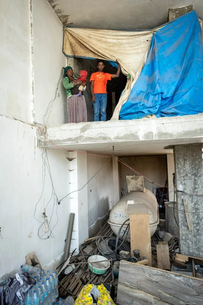 Familie steht vor ihrer Unterkunft auf einer Baustelle 