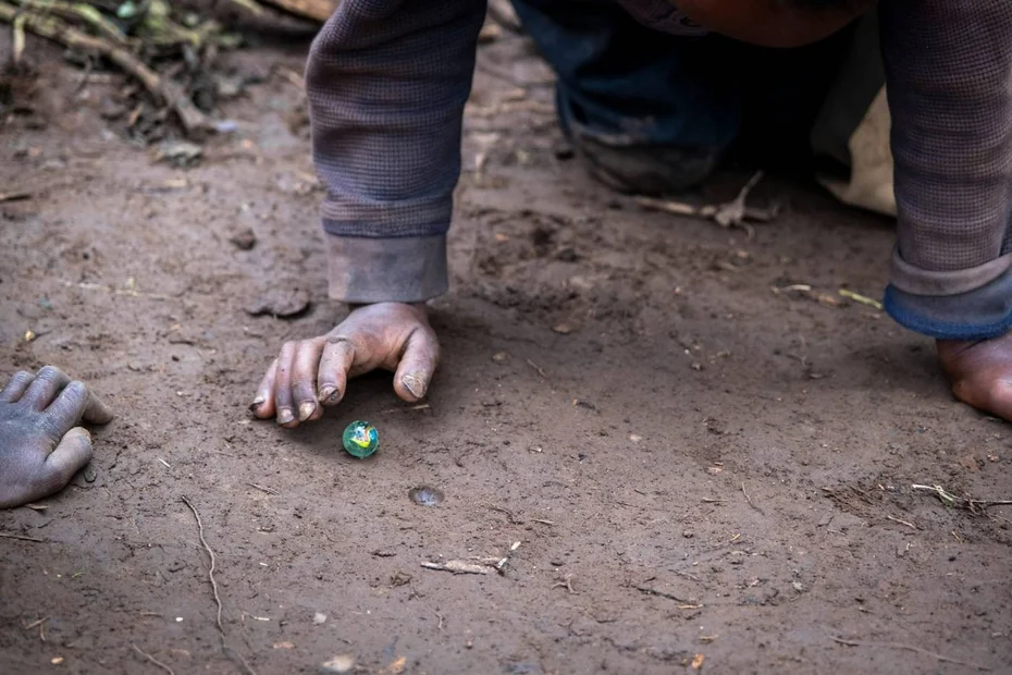 Kind spielt mit einer Murmel am Boden