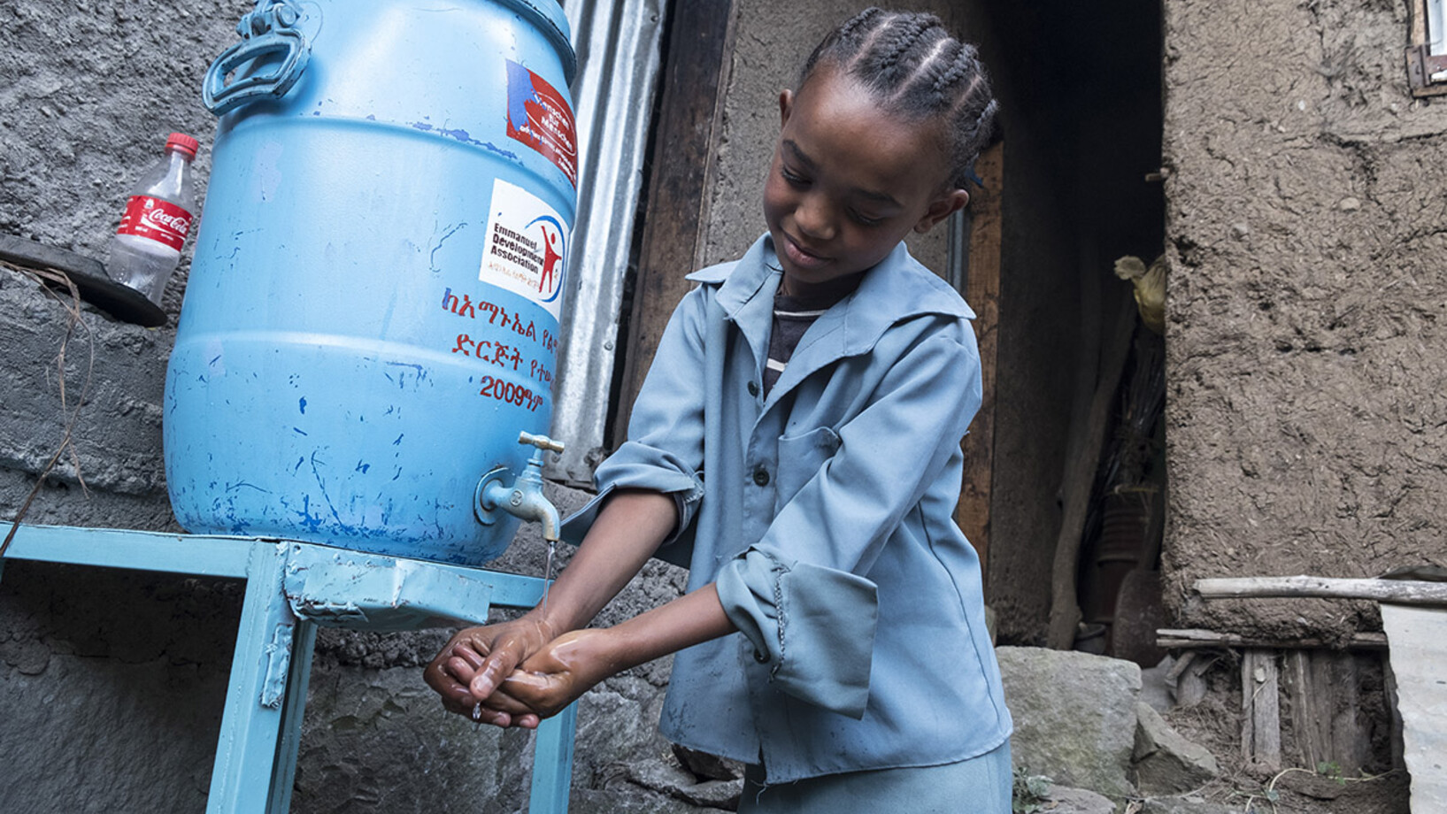 Mädchen wäscht ihre Hände dank einem Wasserkanister von der Stiftung