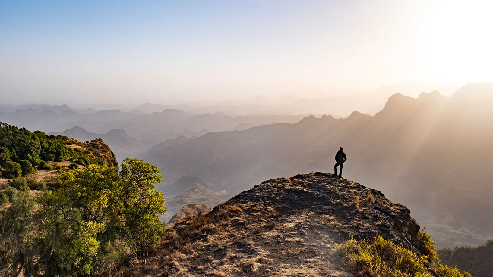 Mann auf Berg mit Sonnenstrahlen