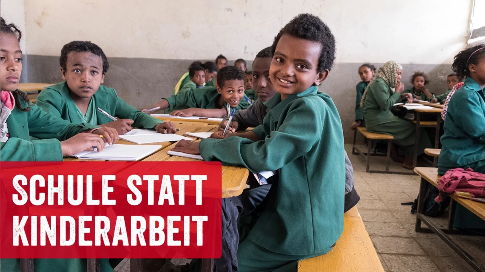 Das Mädchen Kanaan im Klassenzimmer in grüner Schuluniform