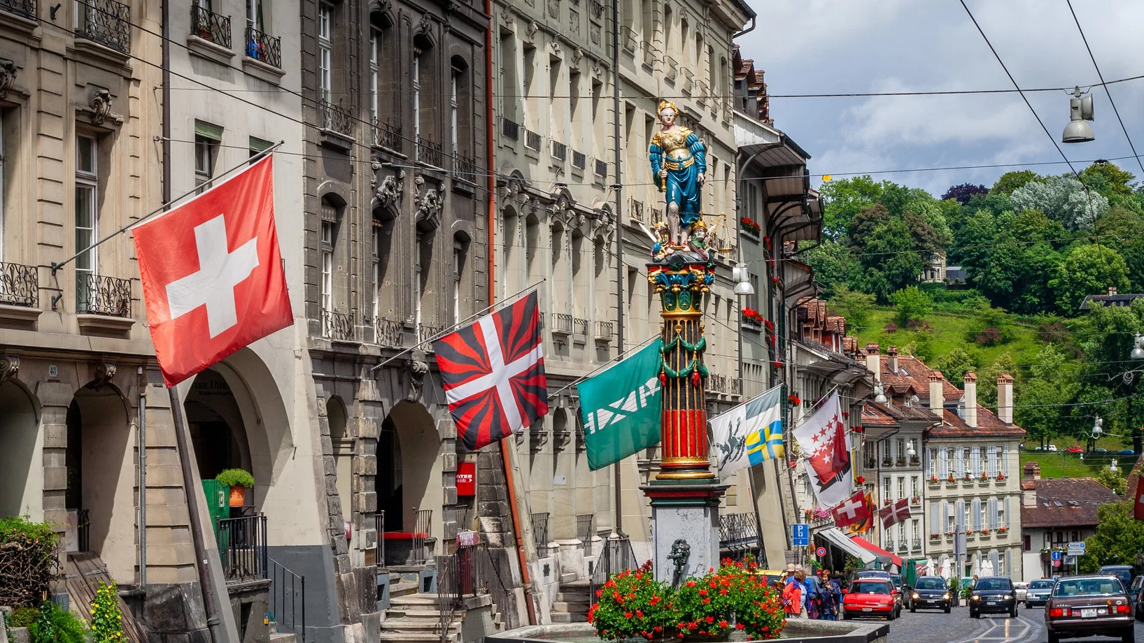 Flags on townhouses and a statue on a fountain